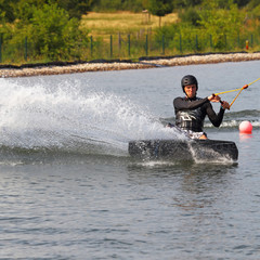 Mann Sportler beim Wakeboarden Wasser spritzen