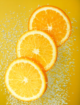 Fresh orange dropped into water with bubbles
