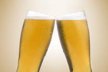 Pair of beer glasses making a toast. Beer splash