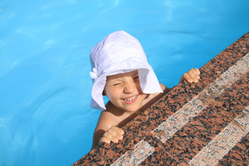 young girl in the hat swims in the swimming pool