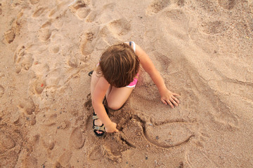young girl paints on the sand