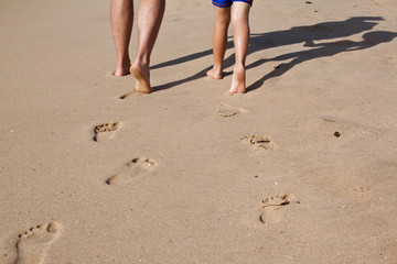 Footprints in sand of father and son walking on the beach