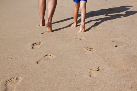 Footprints In Sand Of Father And Son Walking On The Beach