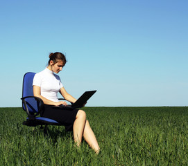 Businesswoman resting with laptop at the green meadow