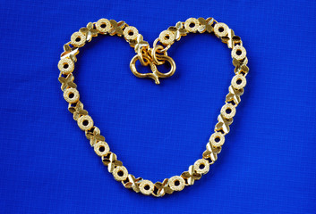 Fototapeta na wymiar Close up view of a 24K gold bracelet isolated on blue