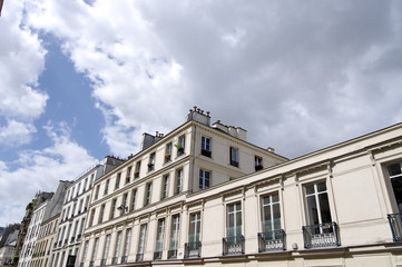 Immeuble dans une rue de Paris, ciel nuageux.