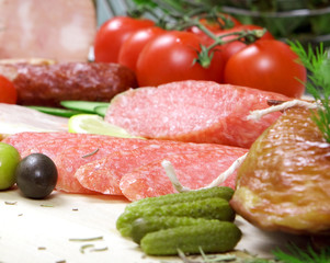 The cut sausage of a salami with cucumbers and tomatoes