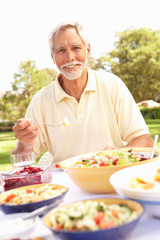 Senior Man Enjoying Meal In Garden