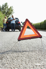 Couple Broken Down On Country Road With Hazard Warning Sign