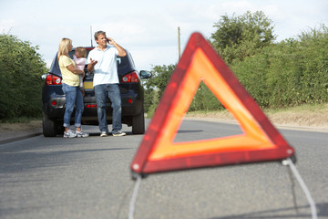 Family Broken Down On Country Road With Hazard Warning Sign