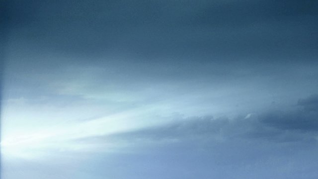 Cloud FX306: Time lapse clouds drift across a hazy blue sky.