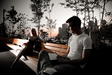 Young attractive couple sit next to each other on a park bench