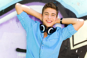 Young guy leaning on graffiti wall
