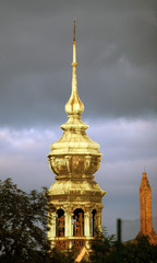 Golden tower of the church in the cloudy sky