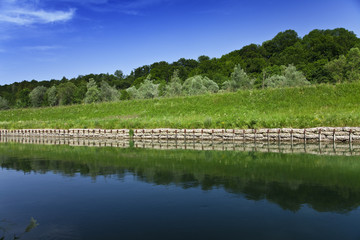 Ufer am Fluss Isar mit grünem Gras und blauem Himmel