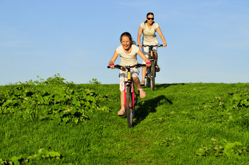 Mother and her dauhgter riding on a bicycles