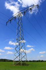 electrical tower green field blue sky white clouds