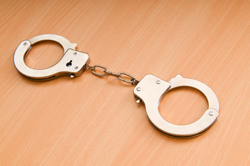 Metal handcuffs on the wooden background
