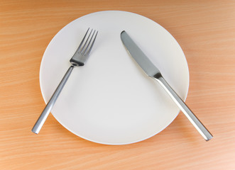 Plate with utensils on wooden table