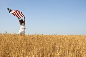 Beautiful young girl holding an American flag in the wind