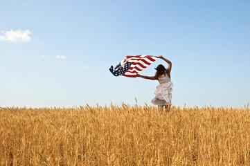 Beautiful young girl holding an American flag in the wind