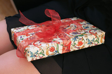 Geschenkpaket mit Schleife auf Mädchenknien