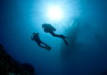 Fotobehang scuba divers silouetted by sun ball © JonMilnes