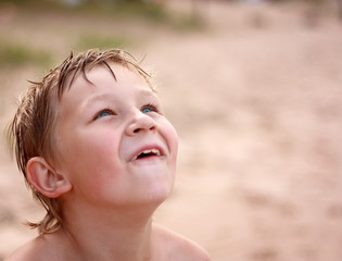 Portrait of a seven years old blond boy playing on the beach