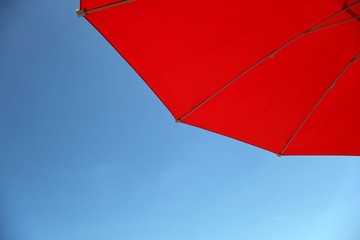 Roter Sonnenschirm vor blauem Himmel