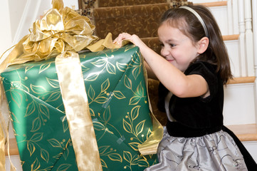 Adorable litle brunette girl with a Christmas present