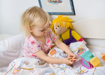 little girl in bed  with toys - obrazy, fototapety, plakaty