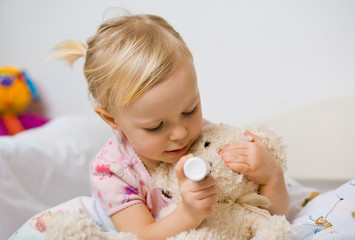 little girl in bed playing with teddy bear