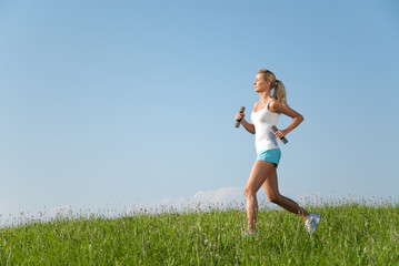 junge frau beim laufen in der natur unter blauem himmel