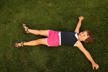 young girl lie on green grass