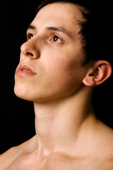 Close up portrait of pensive young man on black background