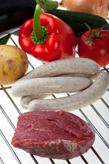 rohes Fleisch, Wurst und Gemüse auf dem Rost