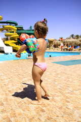 a little girl goes near the swimming pool - obrazy, fototapety, plakaty