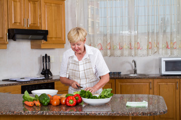 senior woman making a healthy salad in kitchen