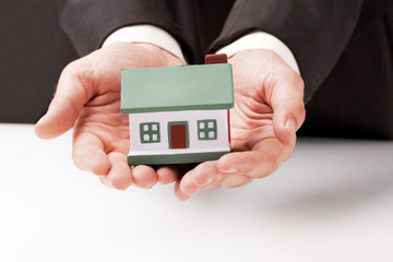 businessman holding a toy house, real estate presentation