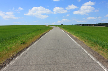 road green cornfield blue sky white clouds
