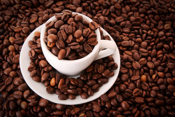 Fototapeta na wymiar Small white cup of coffee with coffee grain on grain background