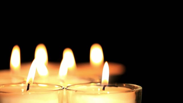 White candles burning over black background