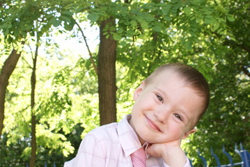 The boy with the tie looks straight ahead, smiling