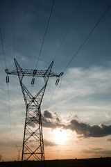 High woltage pylons with wires and sunset