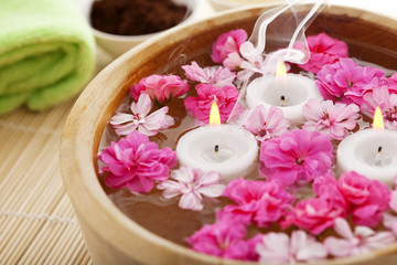 Spa therapy, flowers in water, on a bamboo mat.