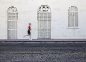 Fast paced man runs down city street.