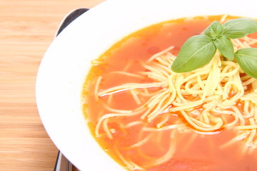Tomato soup with macaroni decorated with basil and a spoon