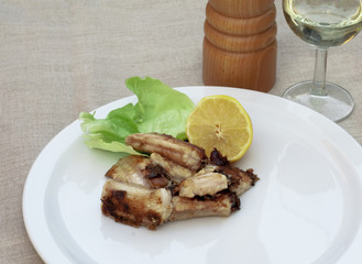 Meal of fried conger with lemon and a glass of white wine