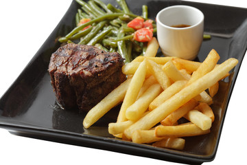 steak and fries on black plate. isolated on a white background