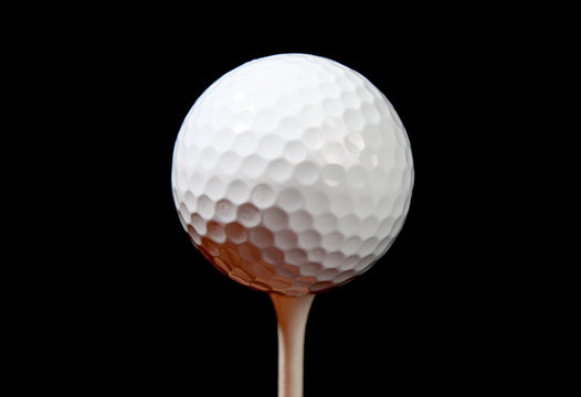 a golf ball on a tee isolated on black